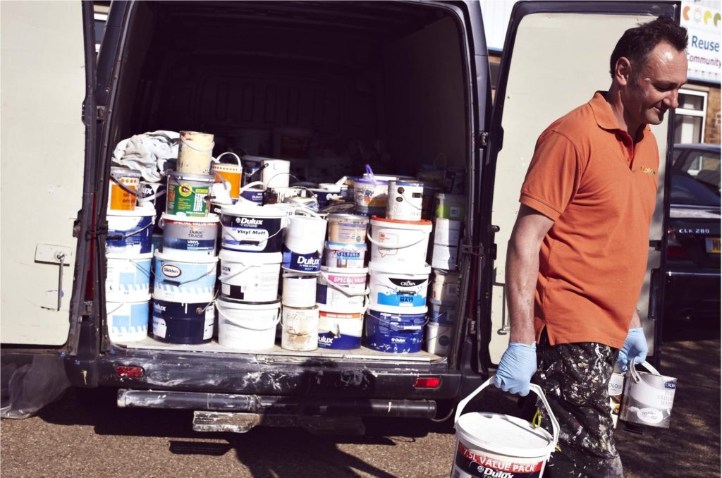 Man unloads van full of paint containers.