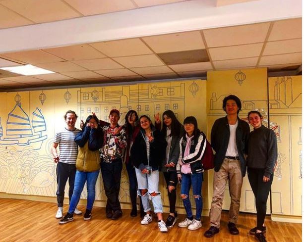 Members of the London Chinese Community Centre stand in front of a newly painted mural using cheap and reusable paint from Regis Road Household Waste Recycling Centre