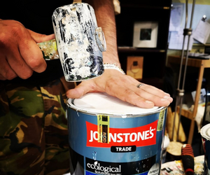 Using a rubber mallet to seal paint tins