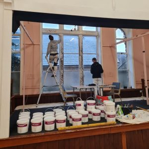 ReColour pots of paint on display while the Trades4Care team work in the background to decorate the church hall 