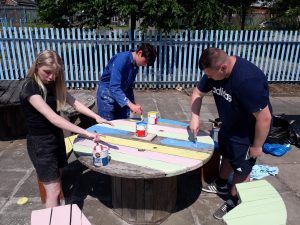 Prescot Prince's Trust team working to upcycle benches and table with paint from Community RePaint Liverpool.